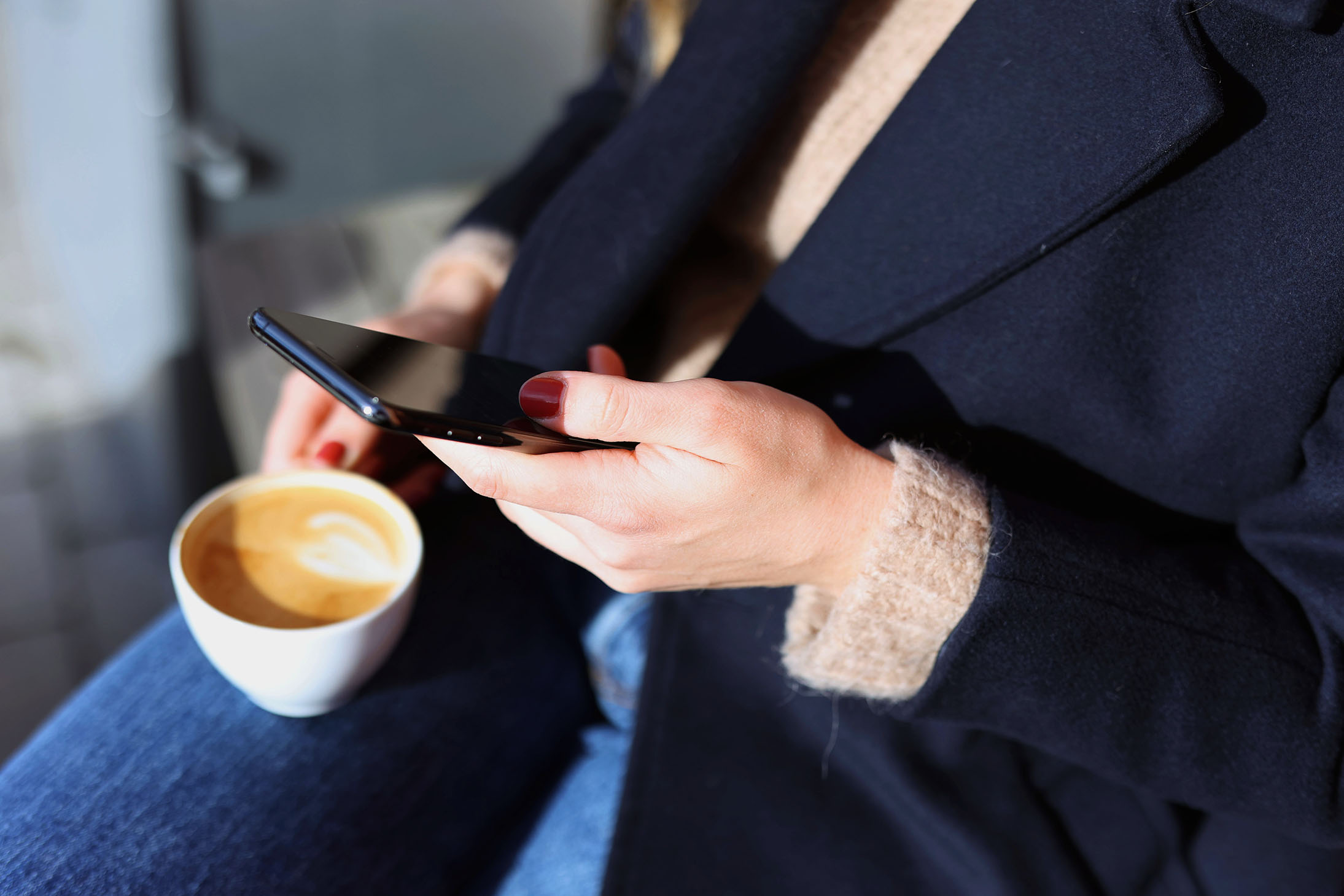Person som håller i en kaffekopp och mobil
