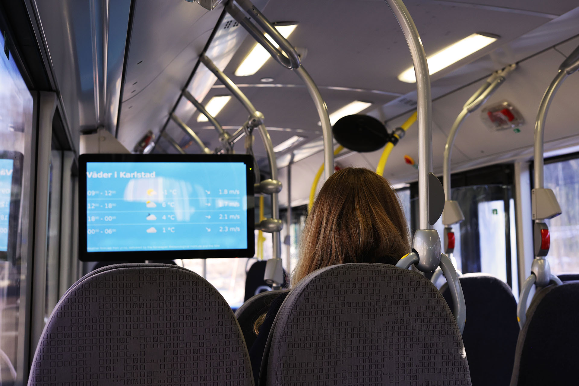 person tittar på buss-tv i stadsbuss